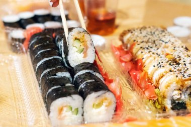 Yemek suşisi rulosu, yemek çubuklarıyla yakın plan.