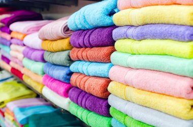Mağazadaki rafta renkli havlular var.