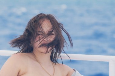 Çilli güzel bir kızın portresi, rüzgâr mavi denizin arka planında saç çıkarır.