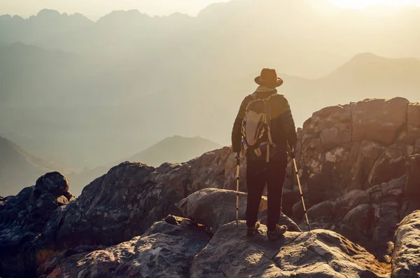 Egy ember, aki egy sziklafal szélén áll Mózes hegyén, és nézi a napfelkeltét Egyiptom hegyeiben. — Stock Fotó
