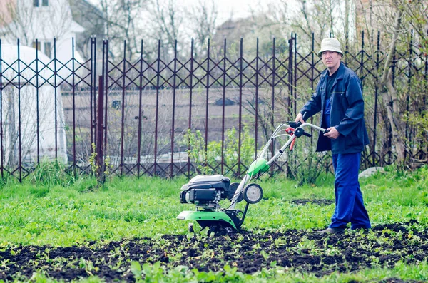 A man plows the land with a cultivator in a spring garden Stock Picture