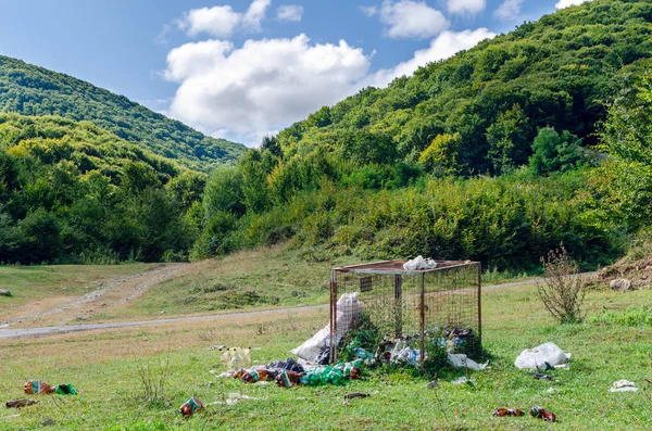 Śmieci rozrzucone wokół śmietnika w naturze, zanieczyszczenie środowiska — Zdjęcie stockowe