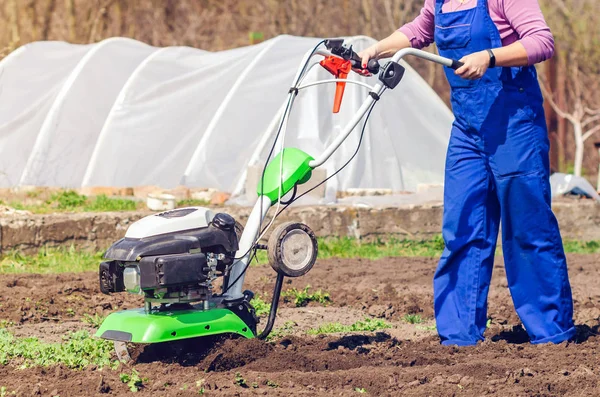 Jong meisje ploegt het land met een cultivator in de lente tuin — Stockfoto