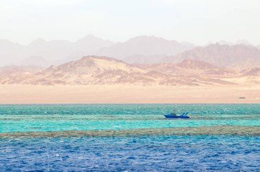 Ras Mohammed Ulusal Parkı, Mısır 'da, dağların ve denizin arka planında küçük bir tekne..