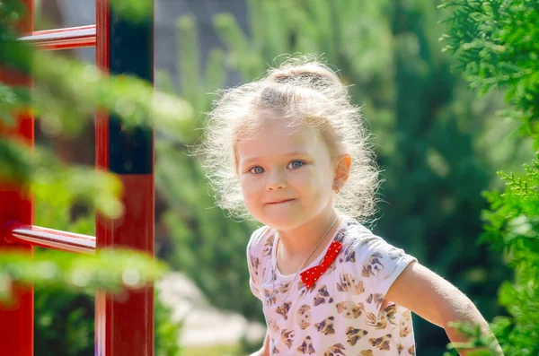 Portrait of a little girl exercising on a horizontal bar on a sports field in the sunlight. — Stock Image Portrait Little Girl Exercising Horizontal Bar Sports Field Sunlight Stock Photo