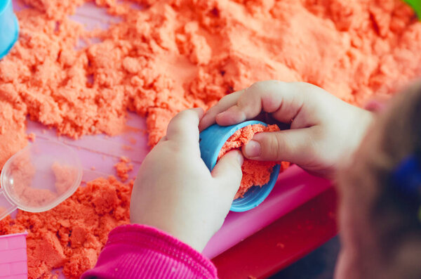 Руки ребенка играют с кинетическим песком
.