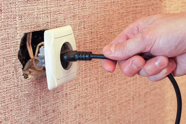 Hand disconnects or connects the plug to a broken outlet, risk of electric shock.