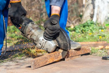 İşçi bir açı öğütücüyle metali keser.