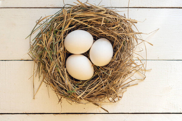 Three white chicken eggs in a nest.