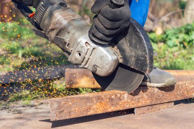 İşçi bir açı öğütücüyle metali keser.