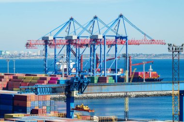 İskele kargo vinci bir konteynırı kargo gemisine yüklüyor..