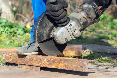 İşçi bir açı öğütücüyle metali keser.