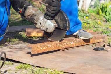 İşçi bir açı öğütücüyle metali keser.