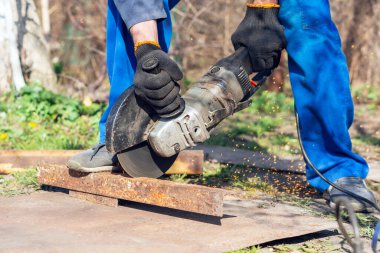 İşçi bir açı öğütücüyle metali keser.