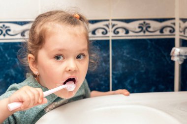 Küçük kız sabah dişlerini banyoda fırçalıyor..