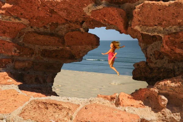 Flying woman view through hole in rocks — Stock Photo, Image