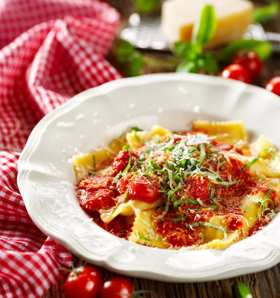 Ravioli coberto com molho de tomate, queijo grana padano e manjericão fresco — Fotografia de Stock