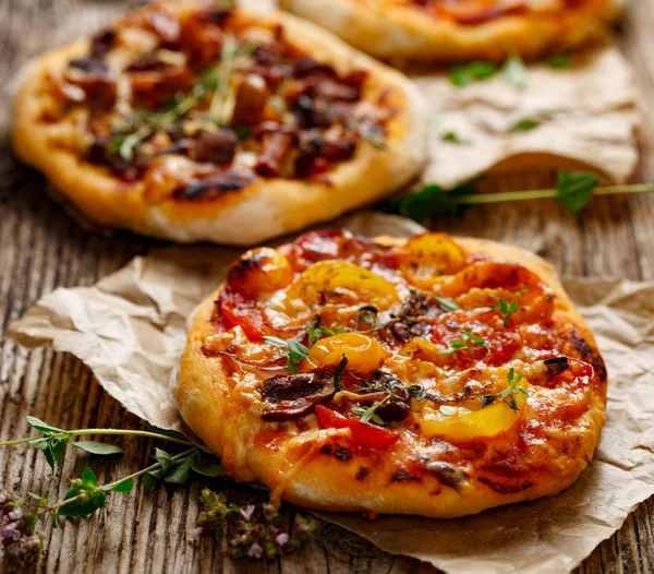 Small homemade vegetable pizza with addition of grilled bell pepper, tomatoes, cheese and herbs