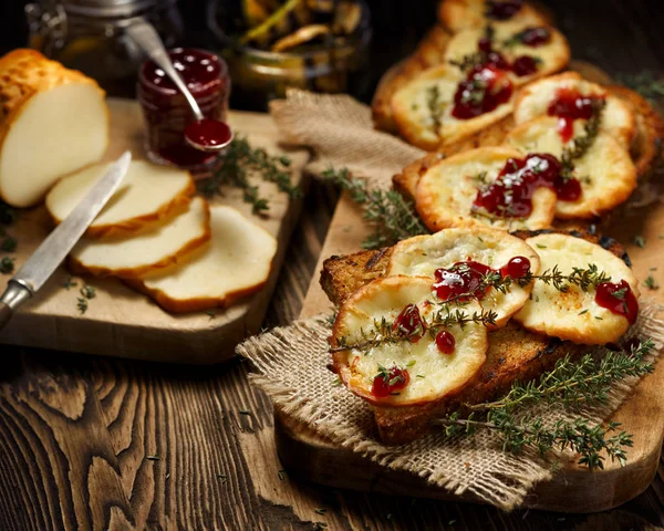 Sandwich a la parrilla con queso de oveja ahumado y mermelada de arándanos rojos silvestres en una mesa rústica de madera — Foto de Stock