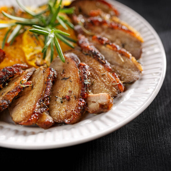 Sliced roasted duck breast on a white plate