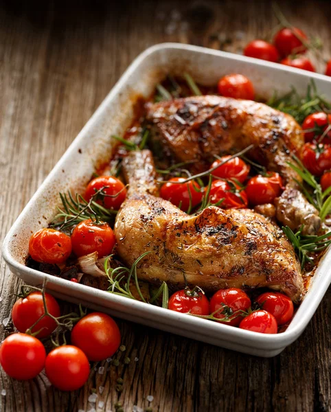 Roast chicken with the addition of cherry tomatoes and herbs in a casserole dish — Stock Photo, Image