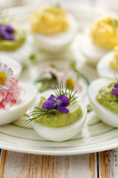 Huevo diabólico relleno de aguacate, decorado con eneldo fresco y violeta comestible —  Fotos de Stock