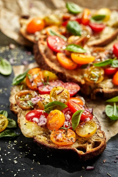 Bruschetta s barevnými cherry rajčaty a čerstvou bazalkou, vegetariánské jídlo — Stock fotografie