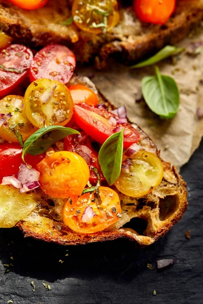 Bruschetta con coloridos tomates cherry y albahaca fresca, comida vegetariana, primer plano —  Fotos de Stock