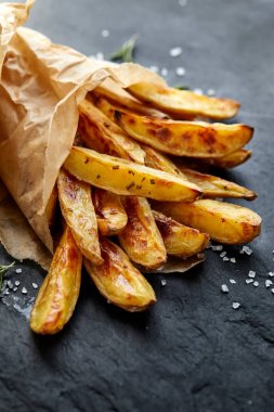 Ayrıca deniz tuzu siyah bir arka plan, üstten görünüm ile fırında patates kızartması
