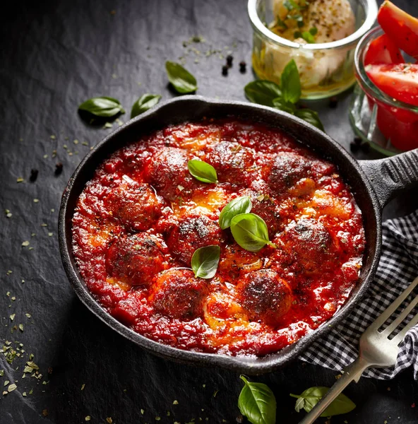 Almôndegas em molho de tomate com queijo de adição e manjericão fresco na panela de ferro — Fotografia de Stock