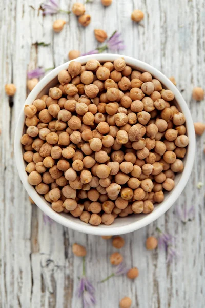 Garbanzos en un tazón blanco sobre una mesa de madera, vista superior — Foto de Stock