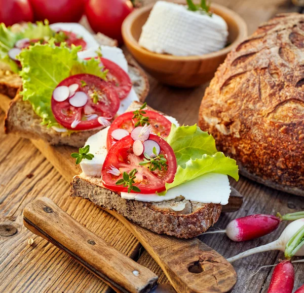 Вегетарианские сэндвичи с добавлением сыра, помидоров и салата на деревенском деревянном столе — стоковое фото