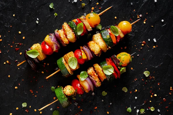 Brochettes végétariennes au fromage halloumi et légumes mélangés sur fond noir, vue de dessus — Photo