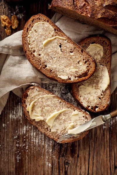 Kromki chleba zakwas rustykalny z domu masło na drewnianym stole — Zdjęcie stockowe
