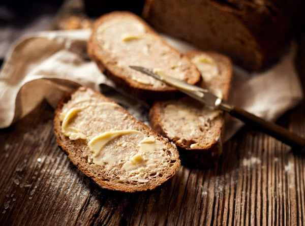 Slices of rustic sourdough bread with homemade butter on wooden table — Stock Photo, Image