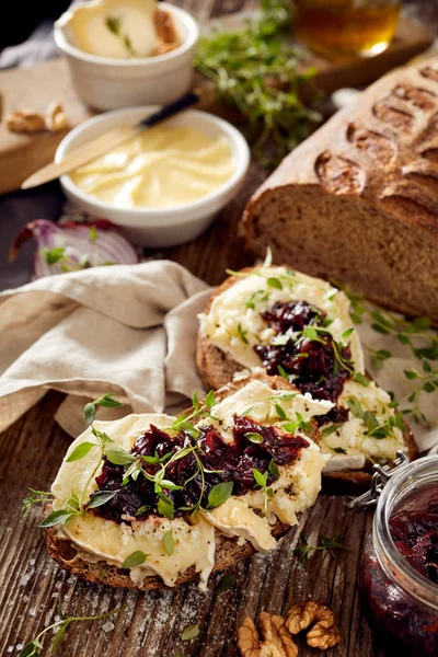 Kanapki z rustykalny chleb z serem kozim, karmelizowanego Cebula czerwony dżem i świeżego tymianku na drewnianym stole — Zdjęcie stockowe