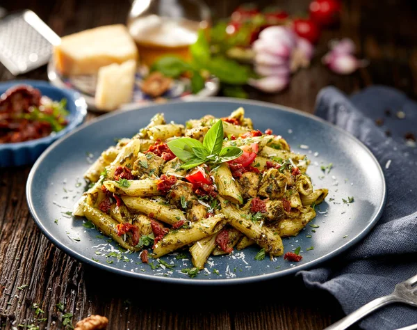 Massa Penne com espinafre, tomates secos ao sol e frango, polvilhada com queijo parmesão e salsa fresca — Fotografia de Stock