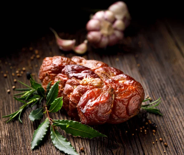 Jamón ahumado sobre una mesa rústica de madera con adición de hierbas aromáticas frescas —  Fotos de Stock