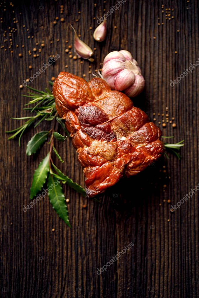 Jamón ahumado sobre una mesa rústica de madera con adición de hierbas