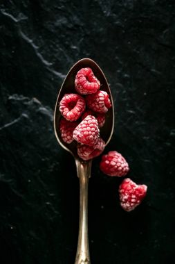 Bir kaşık üzerinde Dondurulmuş ahududu, siyah taş arka plan, üst görünümü