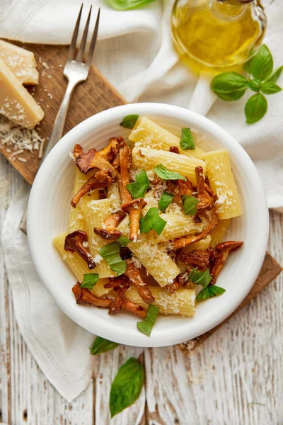 Rigatoni makarna Cantharellus cibarius mantar, parmesan peyniri ve beyaz bir plaka üzerinde taze fesleğen — Stok fotoğraf