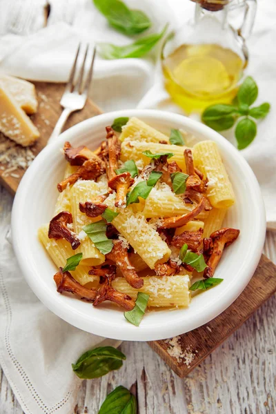 Rigatoni pasta met cantharellen paddestoelen, Parmezaanse kaas en verse basilicum op een witte plaat — Stockfoto