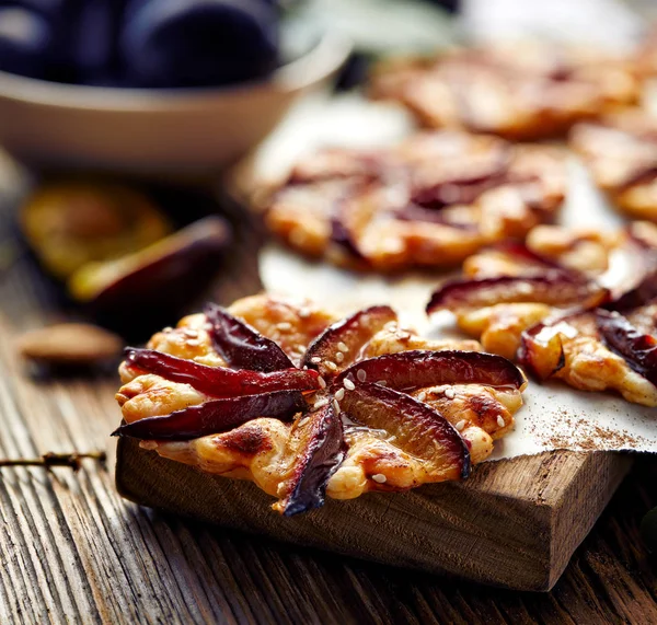 Tarty śliwkowe z cynamonem na drewnianym stole, deser z ciasta francuskiego i owoce — Zdjęcie stockowe