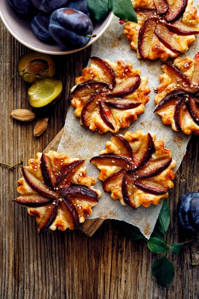Crostate di prugne con cannella su un tavolo di legno, delizioso dessert con pasta sfoglia e frutta — Foto Stock