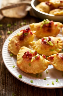 Domuz eti greaves ve beyaz bir plaka üzerinde taze otlar pişmiş köfte lor peynir ve patates ile doldurulmuş serpilir