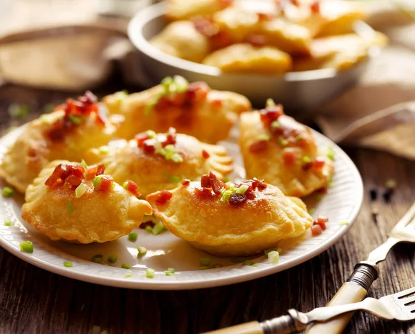 Gebackene Knödel gefüllt mit Quark und Kartoffeln, bestreut mit Schweinegrieben und frischen Kräutern auf einem weißen Teller — Stockfoto