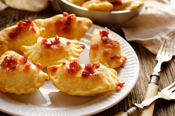 Gebackene Knödel gefüllt mit Käse und Kartoffeln bestreut mit Schweinegrieben auf einem weißen Teller — Stockfoto