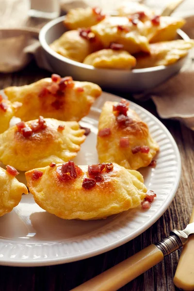 Albóndigas al horno rellenas de queso y patatas espolvoreadas con chicharrones de cerdo en un plato blanco —  Fotos de Stock