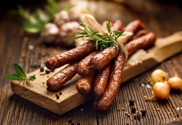 Saucisses sur une table rustique en bois avec ajout d'herbes aromatiques fraîches et d'épices, produit naturel issu de la ferme biologique, produit selon des méthodes traditionnelles — Photo