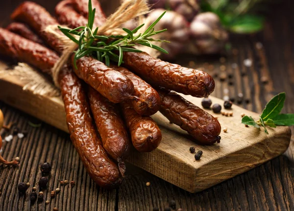 Sausages on a wooden rustic table with addition of fresh aromatic herbs and spices, natural product from organic farm, produced by traditional methods — Stock Photo, Image